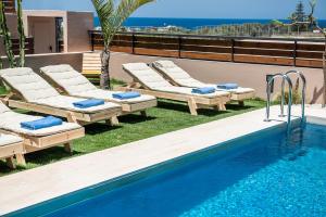 a swimming pool with chaise lounges next to a resort at Fos Villa, a Luxe House with Private Heated Pool in Galatás
