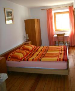 a bedroom with a bed and a desk and a window at Gruppenhaus Thalackerhof in Brunico