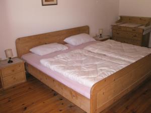 a bedroom with a wooden bed with two night stands at Gruppenhaus Thalackerhof in Brunico