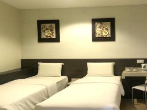 two beds in a room with two pictures on the wall at Alor Boutique Hotel Sdn Bhd in Kuala Lumpur