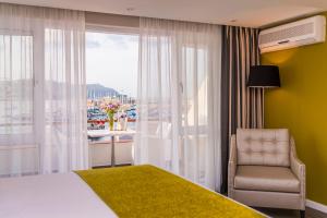 1 dormitorio con cama, ventana y silla en Simon's Town Quayside Hotel, en Simonʼs Town