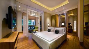 a bedroom with a large white bed and a television at Hotel Fort Canning in Singapore