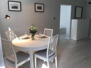 tavolo bianco con sedie e frigorifero bianco da pranzo di Mg Apartamenty - Apartament 51 a Oświęcim