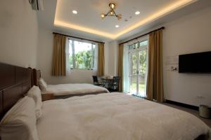 a bedroom with two beds and a flat screen tv at Song Yue Homestay in Yuchi