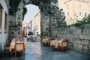 an archway with tables and chairs in a building at Hotel Peristil in Split