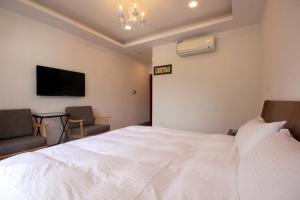 a bedroom with a large white bed and two chairs at Song Yue Homestay in Yuchi +32 photos