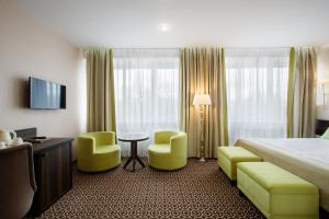 a hotel room with a bed and two chairs and a table at Ural Hotel in Yekaterinburg