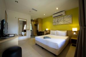 a bedroom with a white bed and a yellow wall at De Palma Resort Kuala Selangor in Kuala Selangor