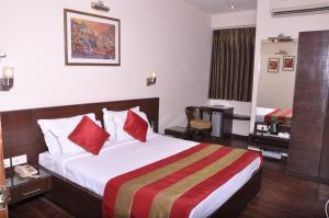 a hotel room with a large bed with red pillows at Crystal Inn in Agra
