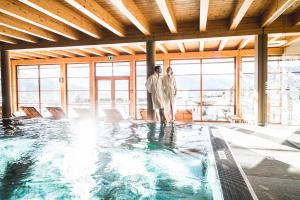 two people standing in front of a swimming pool at Naturhotel Edelweiss Wagrain in Wagrain