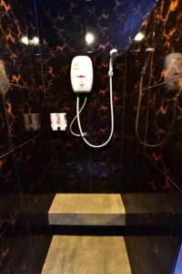 a bathroom with a black tiled wall with a white phone at Love Box Resort in Samut Prakan