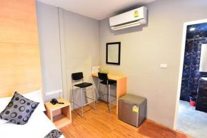 a room with a bed and a desk with chairs at Love Box Resort in Samutprakarn