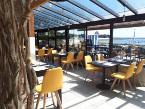 a restaurant with tables and yellow chairs and a patio at Hôtel du Port Bar Restaurant in Sarzeau