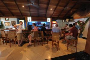 a group of people sitting at a bar in a restaurant at Kokopo Beach Bungalow Resort in Kokopo
