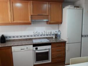 a kitchen with wooden cabinets and a white refrigerator at casudha de juanda in Grao de Castellón