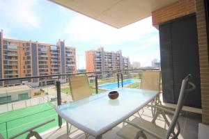 een balkon met een tafel en stoelen en een tennisbaan bij CasaTuris Playa, piscina y parking en Residencial San Juan SJ102 in Alicante