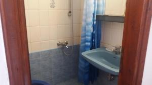 a bathroom with a sink and a blue shower curtain at House Kosmas on the beach in Sarti