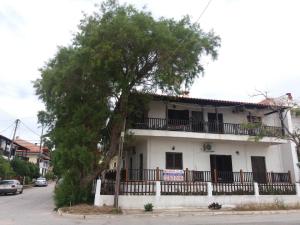 a white house with a tree in front of it at House Kosmas on the beach in Sarti
