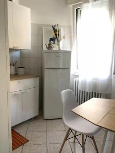 La Casina di Zaira في ريميني: مطبخ أبيض مع طاولة وثلاجة بيضاء
