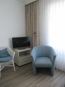 un salon avec une chaise bleue et une télévision dans l'établissement Einzimmerappartement-fuer-zwei-Personen, à Westerland