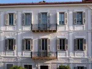 a facade of a white building with windows at Gambello Luxury Rooms in Nafplio