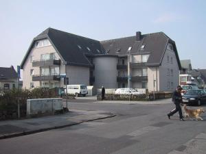 une femme qui marche un chien devant un bâtiment dans l'établissement Einzimmerappartement-fuer-zwei-Personen, à Westerland