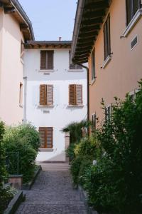 un edificio blanco con persianas marrones y un callejón adoquinado en Attico dell'Artista, en Desenzano del Garda