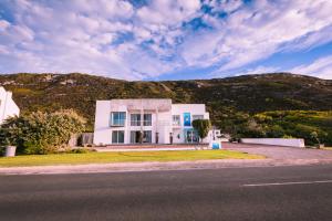 a white house on the side of a road at Agulhas Ocean House in Agulhas