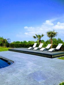 a group of lounge chairs sitting next to a swimming pool at New Cottage & spa de nage Guesthouse in Honfleur