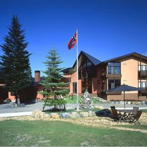 a flag pole in front of a building with a pine tree at Hakuba Alpine Hotel in Hakuba