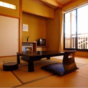 a living room with a table and a large window at Hakuba Alpine Hotel in Hakuba