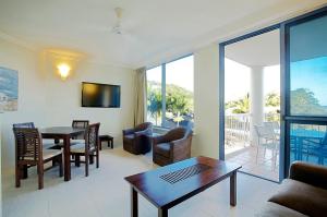 sala de estar con mesa y sillas y sala de estar. en at Whitsunday Vista Holiday Apartments en Airlie Beach