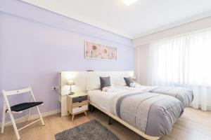 Un dormitorio blanco con dos camas y una silla. en Zurriola - Beachside Comfort, en San Sebastián