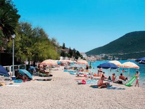 a group of people sitting on a beach with umbrellas at Apartmani Maris in Neum