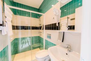a green tiled bathroom with a toilet and a sink at Apartments Statskij Sovetnik in Saint Petersburg
