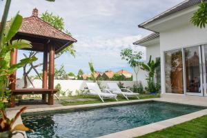 a pool with chairs and a gazebo next to a house at Anna villa 4 in Sanur