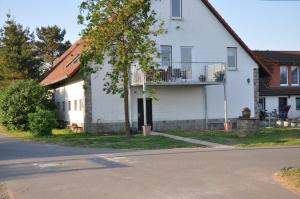 a white house with a balcony on the side of it at FEWO Reitanlage bei Altefähr in Rambin