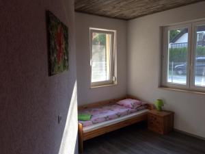 a small bedroom with a bed and two windows at Liget in Balatonföldvár