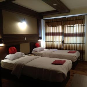 a hotel room with three beds with red pillows at Kumari Guest House in Bhaktapur