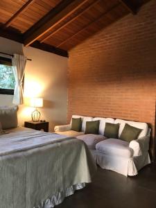 a bedroom with a large bed and a brick wall at Pousada Pinho Bravo in Camanducaia