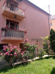 利夫諾的住宿－Apartmani Konta，粉红色的房子,设有阳台和粉红色的鲜花