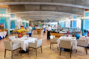 a restaurant with white tables and chairs and a chef at MUR Faro Jandia Fuerteventura & Spa in Morro del Jable