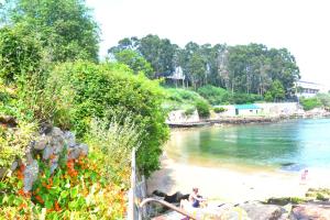 a group of people sitting on a beach near the water at Casa Javson in A Coruña