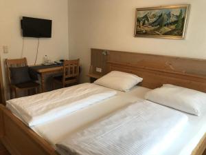 two beds in a room with a desk and a television at Gasthof Stern in Greding