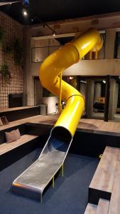 a yellow slide in a room with a bench at Upstairs Hotel in Ostend