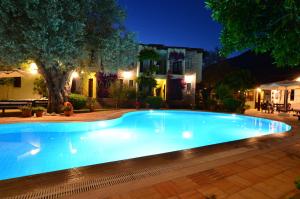 a large blue swimming pool in front of a house at night at Olive Garden Apart Hotel in Göcek