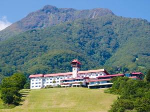 a building on a hill in front of a mountain at Akakura Kanko Hotel in Myoko