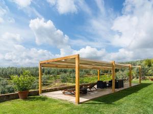a wooden pergola with a table and chairs on a lawn at Exotic Holiday Home in Vinci with Swimming Pool in Vitolini