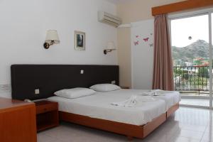 a bedroom with a large bed and a window at Elarin studios & apartments in Faliraki