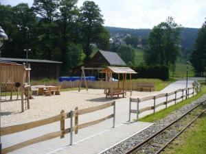 une aire de jeux avec un parc doté de bancs et d'une clôture en bois dans l'établissement Landidyll, à Breitenbrunn/Erzgeb.